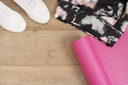 时尚新潮的运动鞋和紧身裤 粉色瑜伽垫 时髦套装 女运动鞋 平躺式运动鞋 顶视图 健身理念 积极的生活方式 身体护理理念 木背景图片