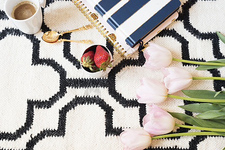 斯堪的纳维亚地毯上的咖啡 草莓 笔记本 粉色郁金香和金汤匙 白色黑色图案和金色主题 生活方式的概念 复制空间条纹房子装饰公寓地面图片