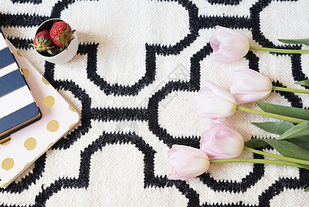斯堪的纳维亚地毯上的咖啡 草莓 笔记本 粉色郁金香和金汤匙 白色黑色图案和金色主题 生活方式的概念 复制空间金子家具地面公寓条纹图片