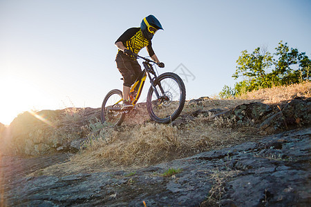 赛车手骑着山上摩托 在夏日落石轨的夜晚 极端运动和Enduro自行车概念骑士男性活动金子下坡速度爬坡冒险车轮山地车图片