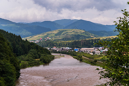 多云天空背景下的山景 山河全景 村庄 绿色草地和斜坡图片