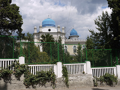 Sultan的地产在金属栅栏后面的一个绿色公园里 蓝天背景之下图片