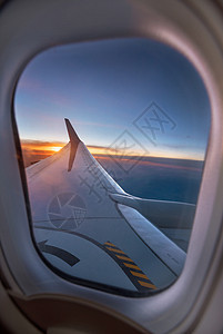 日落时飞机机翼穿过窗户 在充满活力的夕阳下天空高清图片素材