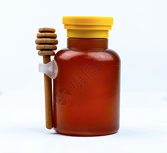 玻璃瓶中的蜂蜜 黄色盖帽和木棍在白色背景下与空白标签隔离 美味的早餐食品概念 蜂蜜产品的包装设计元素图片