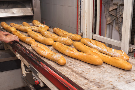 贝克从工业烤箱里拿出新鲜面包面包架子产品机械糕点面团生产男人食品工人厨房图片