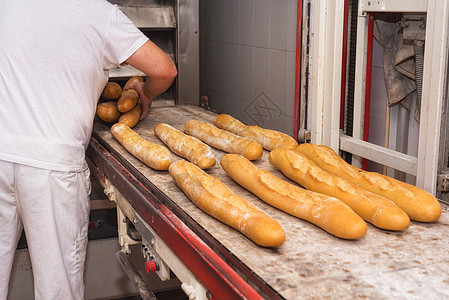 贝克从工业烤箱里拿出新鲜面包面包火炉工厂烹饪产品小麦面团面包师面粉职场制造业图片