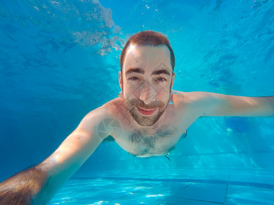 水下自拍英俊的年轻人 在游泳池的水下潜水闲暇游泳者橙子蓝色男性乐趣健康运动游泳水池背景