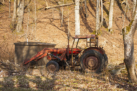 废弃在森林中的红色旧拖拉机图片