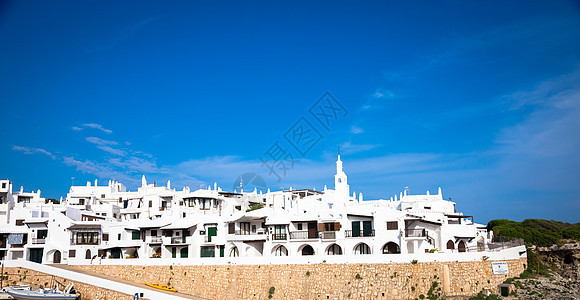 西班牙Menorca传统村天空晴天城市蓝色粉饰海岸旅游街道石头住宅图片