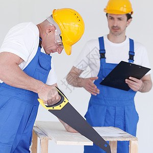 工人用手锯工作承包商建设者职业头盔团队领班装潢师维修木头工匠图片
