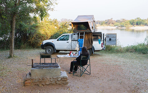 女人在四轮驱动汽车前放松 车上有帐篷睡袋红色桌子越野车辆乐趣露营者荒野椅子季节图片