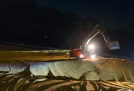 夜间工作挖掘挖土机 在海滩地面移动 以进行维修保养背景