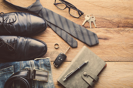 木地板上男人的服装电话眼镜夹克衬衫口袋牛仔裤帽子领带棕色手表图片