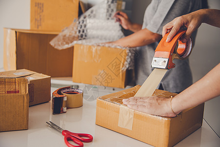 团队工作人员包装在棕色箱子中 将货物交付给客户家庭盒子男性生活磁带邮资开箱女性女士搬迁图片