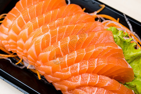 黑盘上切片的生鱼肉盘子红色鱼片寿司食物橙子美食海鲜图片