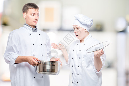 厨师惊讶地看着汤 在锅炉上另一个厨师的锅里图片