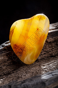 天然琥珀 黄色不透明的天然琥珀 在大片黑石头木头上珠子宏观蜂蜜宝石抛光太阳石黄油分层裂缝材料图片