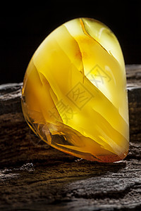 天然琥珀 黄色不透明的天然琥珀 在大片黑石头木头上矿物抛光裂缝化石珠子太阳石黄油蜂蜜琥珀色珠宝图片