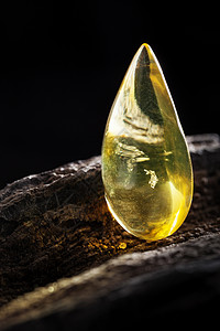天然琥珀 黄色透明的天然琥珀 在大片黑石头木头的一块上蜂蜜反射抛光宝石化石琥珀色太阳石宏观烙印珠宝图片