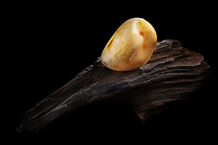 天然琥珀 黄色不透明的天然琥珀 在大片黑石头木头上反射蜂蜜宏观抛光珠子宝石裂缝珠宝化石黄油图片