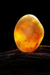 天然琥珀 黄色不透明的天然琥珀 在大片黑石头木头上矿物化石太阳石抛光分层珠子琥珀色蜂蜜宝石裂缝图片