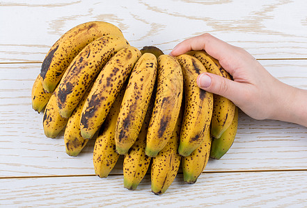 手握着一帮黄发光的香蕉活力热带情调食物饮食水果营养雀斑小吃消化图片