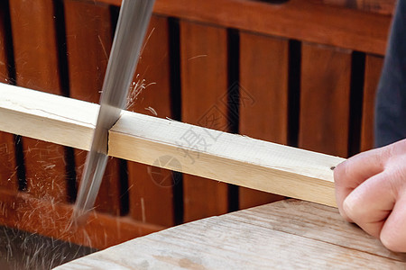 男子的手用木棍锯锯木头木条职业工作乐器男性男人手锯工匠木制品作坊背景图片