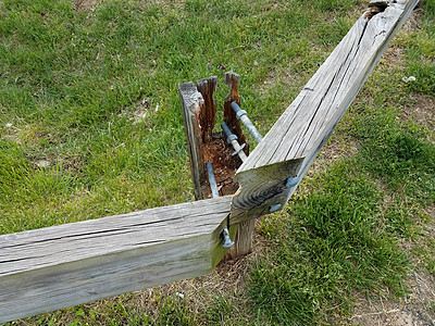 带金属螺钉和绿草的折断木栅栏图片