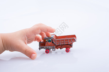 手要抓一辆红色玩具卡车了塑料旅行运输货车车辆司机童年倾倒背景图片