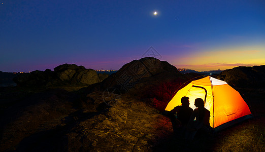 坐在月亮上在山边的博蒂鲁尔晚宴上坐着 坐在不光化帐篷附近 互相看着对方夫妻辉光假期岩石游客女性家庭闲暇远足者冒险背景