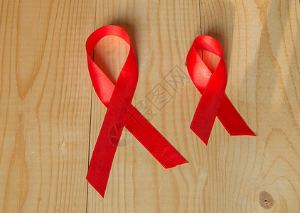 木质背景上的红丝带意识 世界抗击艾滋病日 12 月促进公众支持艾滋病病毒感染者的健康宽容斗争帮助幸存者仪式免疫治愈缺陷团结协会图片