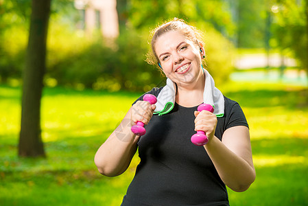 健身时公园里有哑铃的快乐胖女人图片