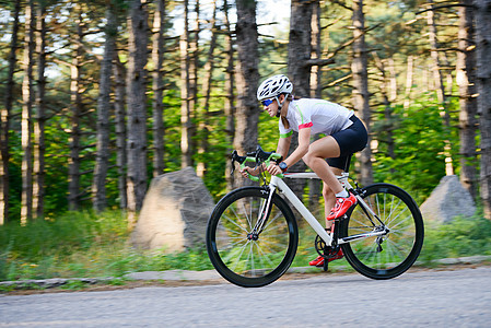 青年女赛车手骑着路自行车在夏日热火的森林中走免费道路 健康生活方式概念女性公园城市自由森林成人街道冒险女孩晴天图片
