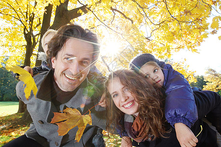 秋天公园的家庭拥抱乐趣孩子们叶子微笑公园幸福骑术孩子季节喜悦图片