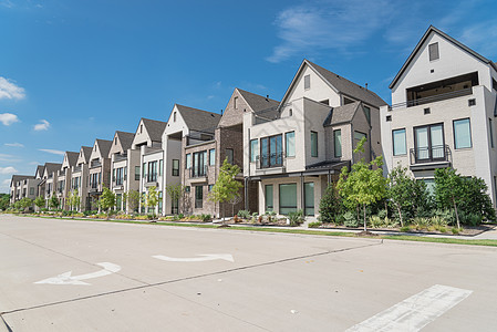 在德克萨斯州达拉斯附近 新建三套单一家庭房屋人行道街道住宅房子房地产草地公寓社区发展入口背景