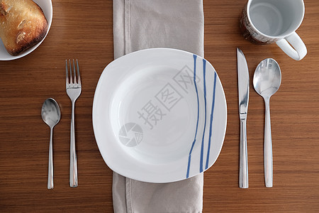 木制桌子上一个餐厅的餐桌茶匙餐具盘子木头杯子早餐装饰餐巾服务蓝色图片