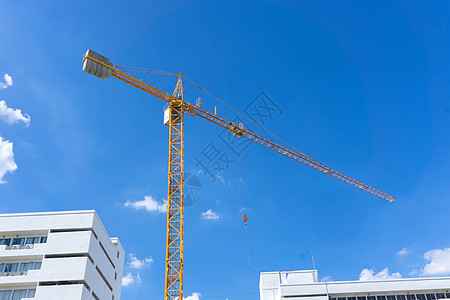 蓝色天空的黄色建筑塔起重机挖掘机公寓工程搬运工商业基础设施活动房地产工作生长图片