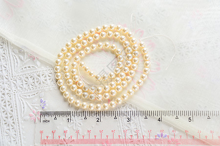 白色布料背景上的珍珠项链 近距离拍摄珠子风格珠宝夹克反射配饰礼物展示宝藏妈妈们图片