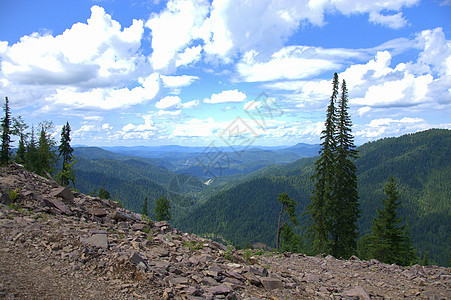 在一座岩石山顶的孤单的松树上 云层下有美丽的山脉景色图片