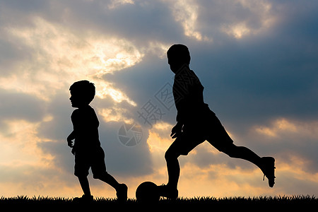 儿童在日落时踢足球图片