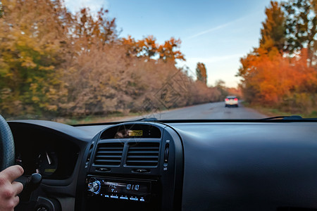 一名男子驾驶一辆汽车在秋天的黄橙黄色路上行驶公园游客司机森林手指交通沥青世界地平线天空图片