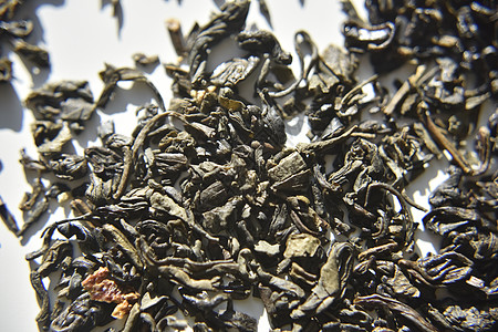 绿茶叶在明亮的光线下白色背景下的干淡绿茶叶阳光香气黑色食物时间冥想叶子发酵背景图片