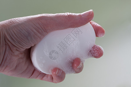手握湿泡沫肥皂棒白色卫生淋浴皮肤酒吧背景图片