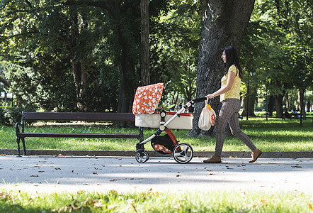 母亲带着婴儿虫在公园里走着孩子幸福闲暇越野车运输母性妈妈女士新生家庭图片
