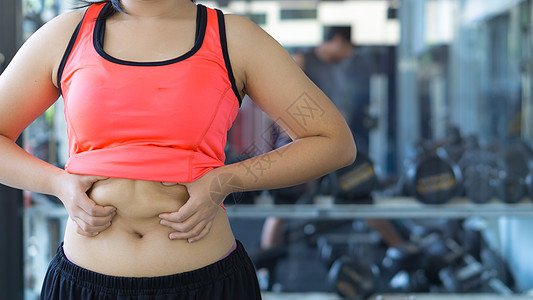 特写女人抱着过多的脂肪腹部 女人超重 abd损失橘皮营养饮食内衣健身房胸罩女性运动体重图片