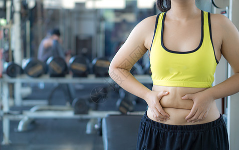 特写女人抱着过多的脂肪腹部 女人超重 abd成人暴饮暴食胸罩营养手臂健身房腰部损失身体运动图片