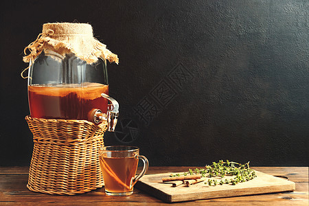 水龙头罐子和深底杯子里的茶饮中发酵的茶图片