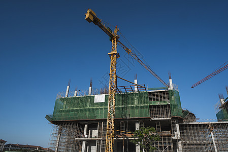 蓝天的起重机和建筑工地 未完工建筑的金属结构施工 塔式起重机用于建造多仓库建筑项目公寓高楼技术商业机器脚手架住宅城市天空图片