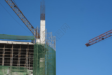 蓝天的起重机和建筑工地 未完工建筑的金属结构施工 塔式起重机用于建造多仓库建筑技术城市天空摩天大楼项目商业高楼住房机器公寓图片