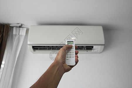 使用遥控器的人的手 手持 rc 和调节安装在白墙上的空调温度 室内舒适温度 健康理念和节能控制通风护发素气候按钮冷却状况办公室活图片